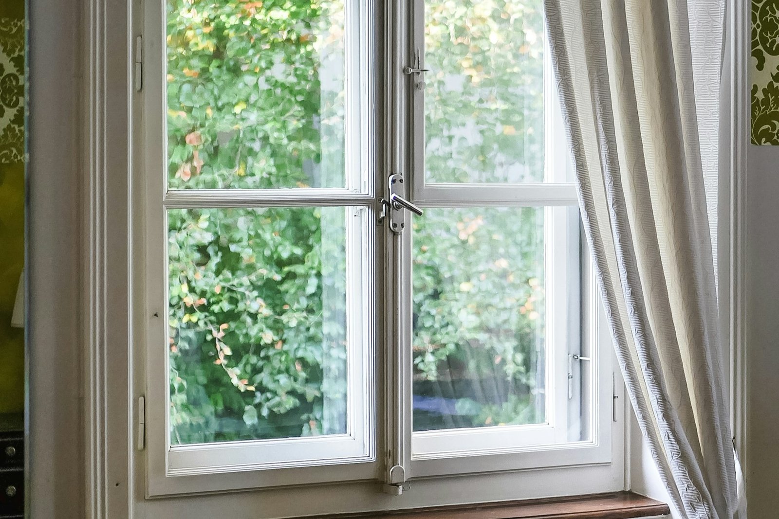 Geöffnetes Fenster mit feuchtem Tuch am Scharnierbereich