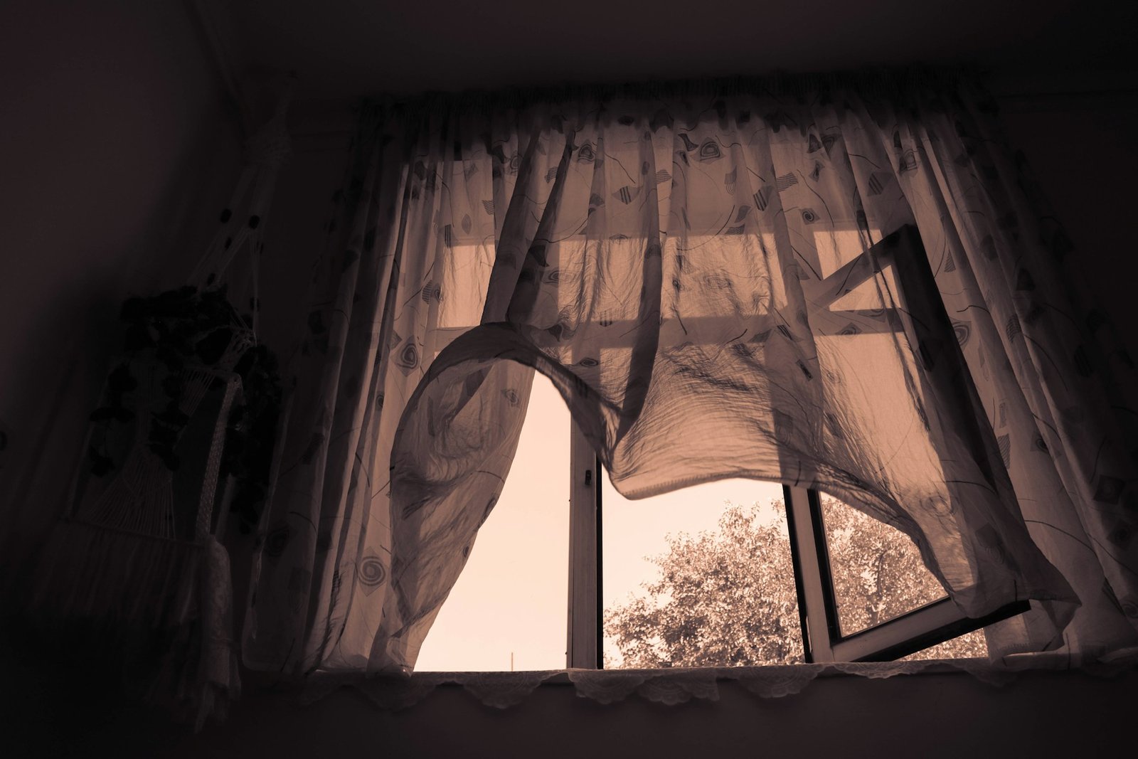 Leicht geöffnetes Fenster mit bewegtem Vorhang durch Wind