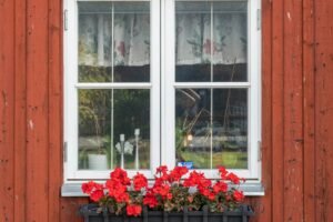 Hand sprüht Schmiermittel auf Fensterbeschlag