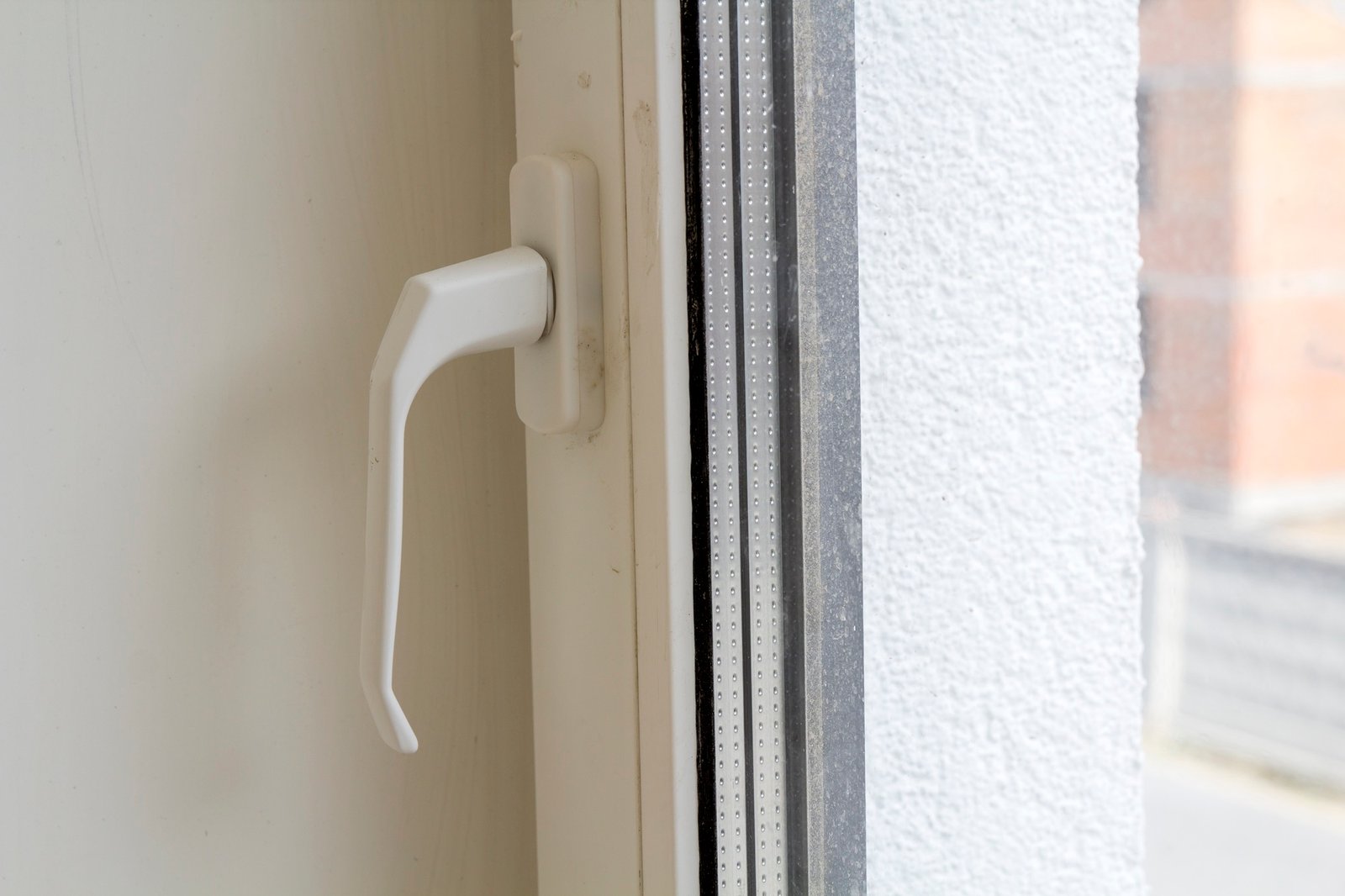 Hand greift einen weißen Fenstergriff